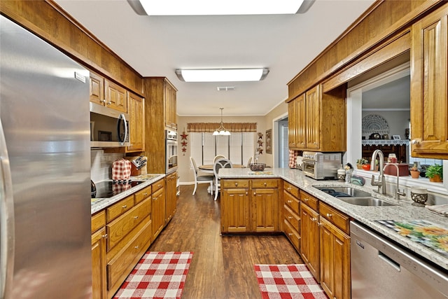 kitchen with stainless steel appliances, a sink, brown cabinetry, and dark wood finished floors