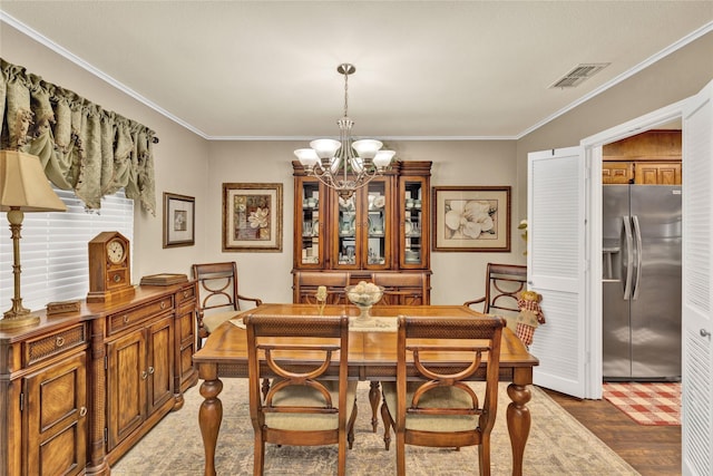 dining room with wood finished floors, visible vents, a notable chandelier, and crown molding