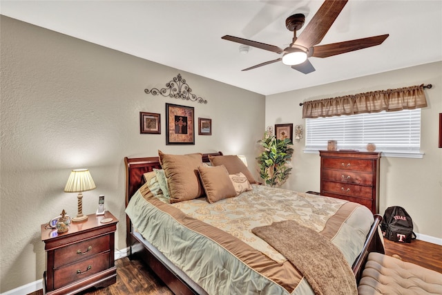 bedroom with dark wood finished floors, a ceiling fan, and baseboards
