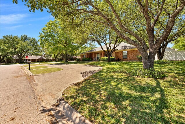 exterior space with fence, brick siding, and a front yard