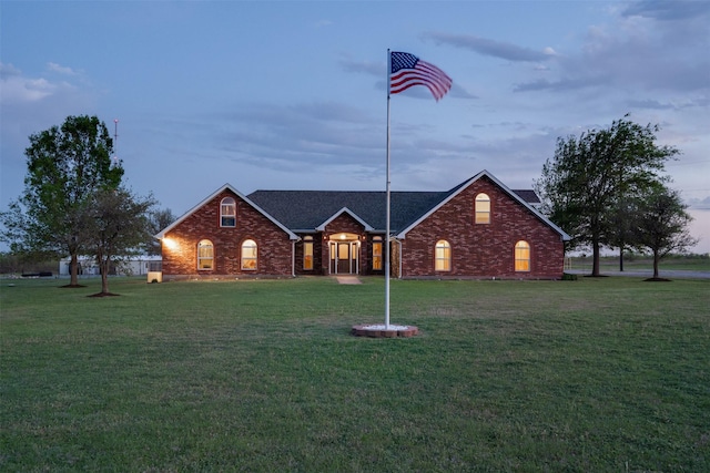 view of front of property with brick siding, roof with shingles, and a front yard
