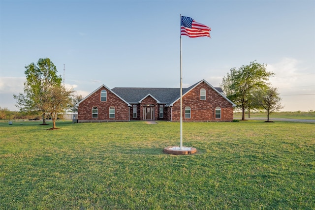 view of front facade featuring brick siding, a shingled roof, and a front yard