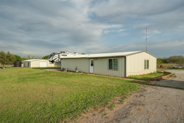 view of front of house featuring metal roof, a front lawn, an outdoor structure, and central AC unit