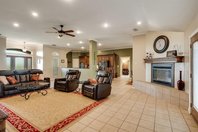 living room featuring a ceiling fan, light tile patterned floors, a tiled fireplace, ornamental molding, and recessed lighting