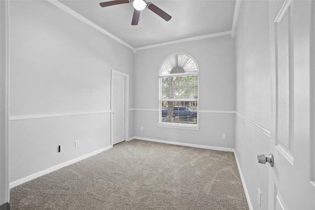 carpeted spare room featuring crown molding, baseboards, and a ceiling fan