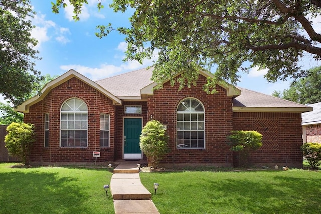 ranch-style home with brick siding, a shingled roof, and a front yard