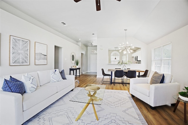 living area featuring wood finished floors, visible vents, lofted ceiling, and ceiling fan with notable chandelier