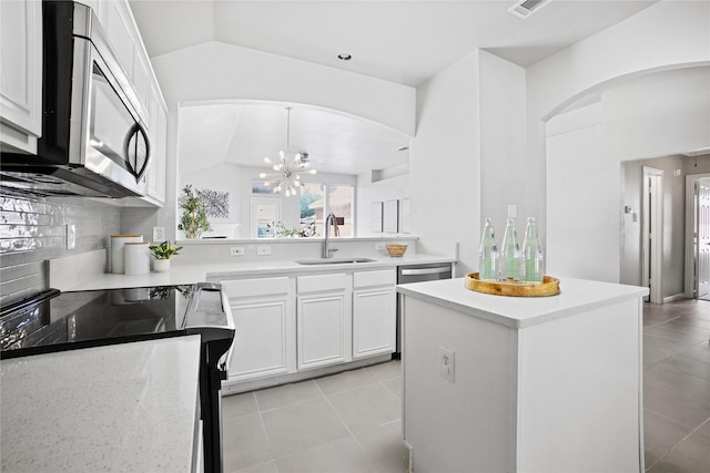 kitchen with white cabinets, a sink, stainless steel microwave, range with electric cooktop, and lofted ceiling