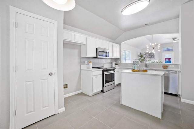 kitchen with lofted ceiling, stainless steel appliances, light countertops, light tile patterned flooring, and white cabinetry