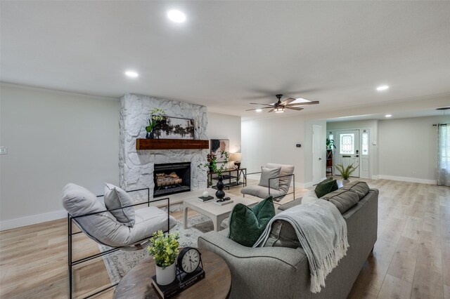 living room with baseboards, light wood-type flooring, recessed lighting, a fireplace, and a ceiling fan