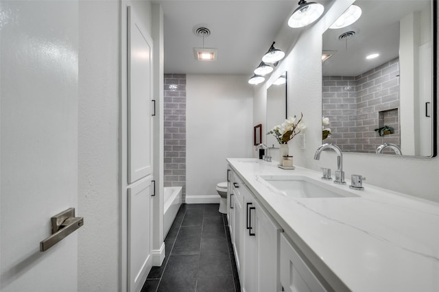 bathroom featuring tile patterned flooring, double vanity, toilet, and baseboards