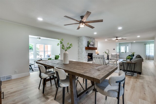 dining space featuring a ceiling fan, a fireplace, recessed lighting, light wood-style flooring, and baseboards