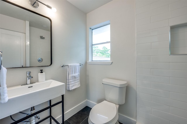 full bathroom with baseboards, toilet, tiled shower, and tile patterned flooring