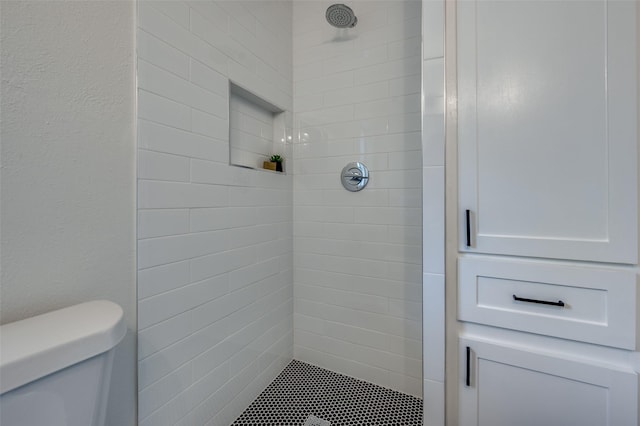full bathroom with tiled shower and toilet