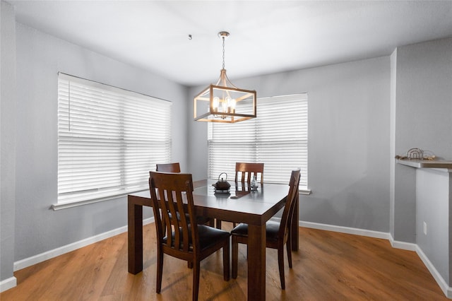 dining space with an inviting chandelier, light wood finished floors, and baseboards