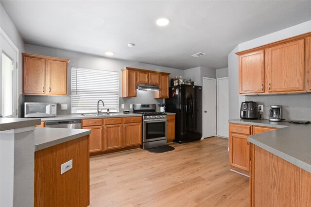 kitchen with a sink, light wood-style flooring, stainless steel appliances, recessed lighting, and under cabinet range hood