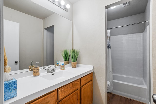full bath with visible vents, vanity, wood finished floors, toilet, and shower / bath combo