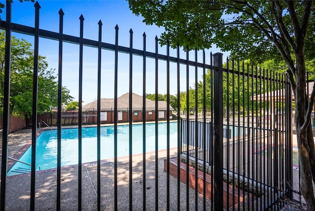 view of gate with a community pool and fence