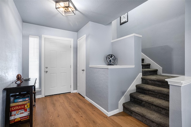 foyer featuring stairway, baseboards, and wood finished floors