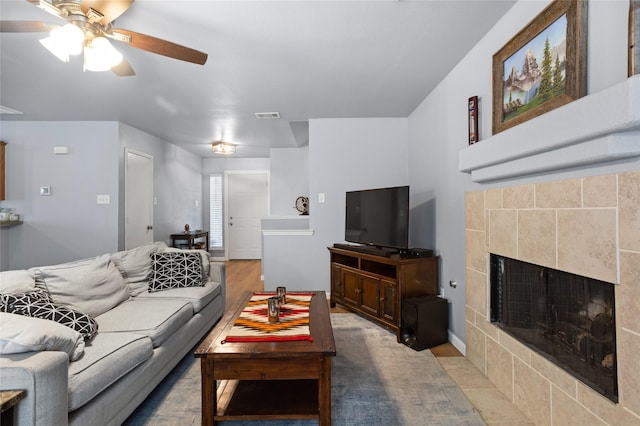 living area featuring ceiling fan, visible vents, wood finished floors, and a fireplace