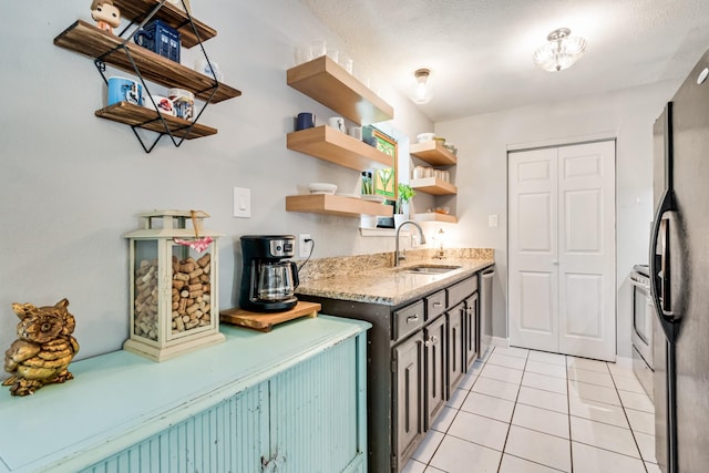 kitchen featuring open shelves, a sink, light tile patterned floors, light stone countertops, and freestanding refrigerator