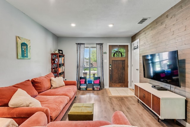 living room featuring wood walls, light wood finished floors, visible vents, and recessed lighting