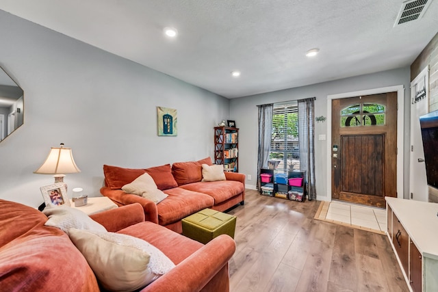 living room featuring light wood finished floors, baseboards, visible vents, and recessed lighting