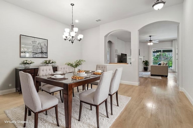 dining area featuring arched walkways, light wood-type flooring, and baseboards