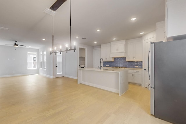 kitchen featuring white cabinets, a sink, decorative backsplash, appliances with stainless steel finishes, and ceiling fan