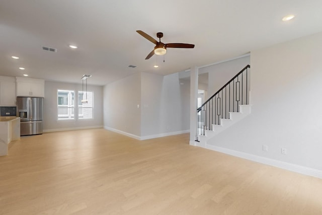 unfurnished living room featuring recessed lighting, light wood finished floors, visible vents, baseboards, and ceiling fan with notable chandelier