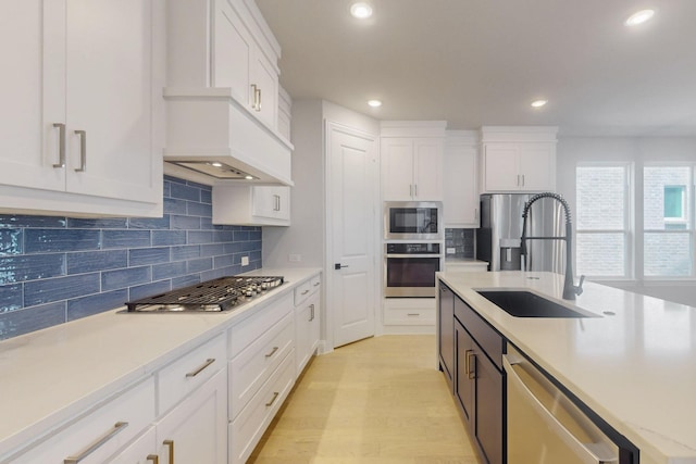kitchen with stainless steel appliances, a sink, white cabinetry, decorative backsplash, and light countertops