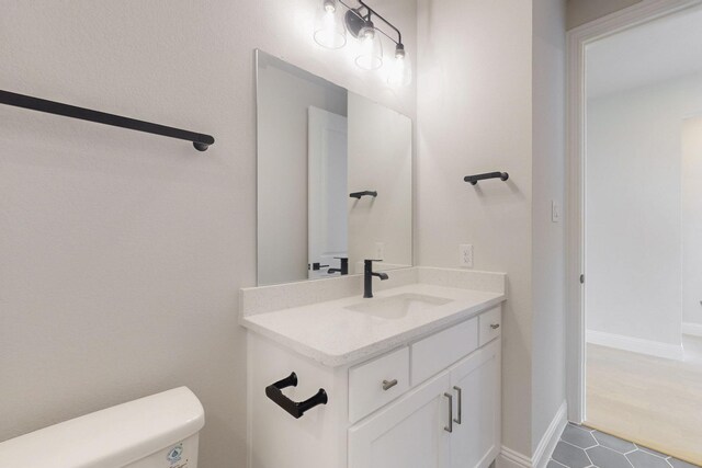 half bath featuring toilet, vanity, and tile patterned floors