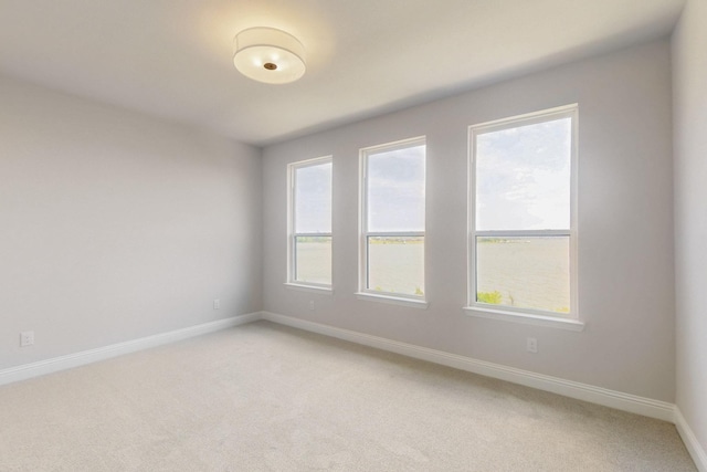 spare room with light carpet and baseboards