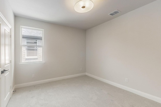 empty room featuring light carpet, visible vents, and baseboards