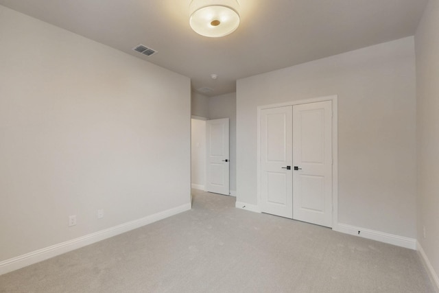 unfurnished bedroom featuring a closet, baseboards, visible vents, and light colored carpet
