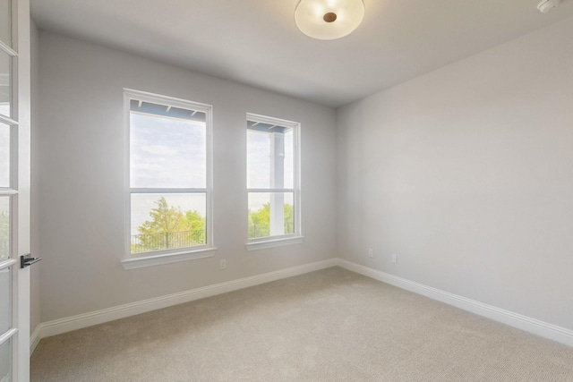 unfurnished room featuring light carpet and baseboards
