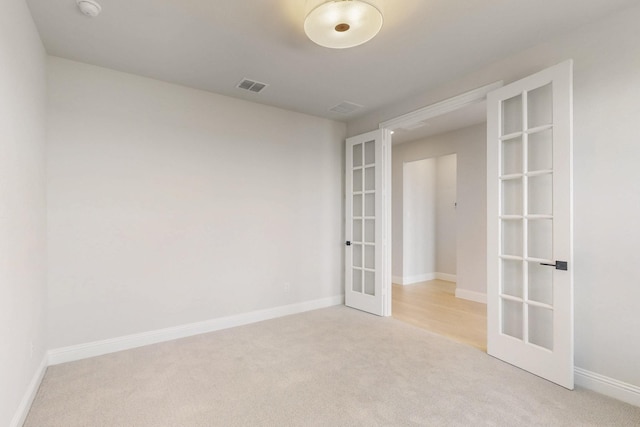 empty room featuring baseboards, french doors, visible vents, and light colored carpet