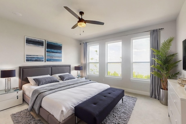 bedroom featuring light carpet, a ceiling fan, and baseboards