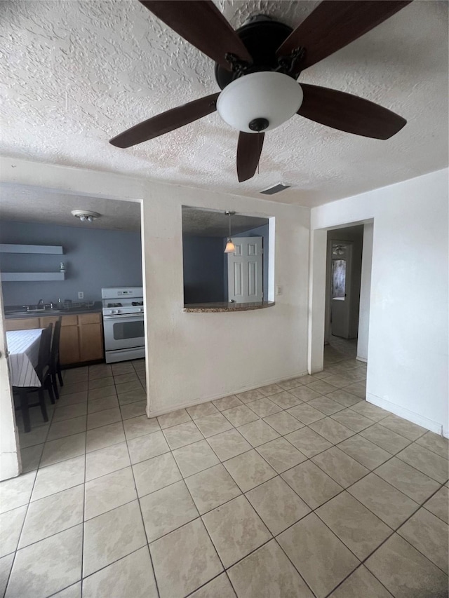 empty room featuring visible vents, a ceiling fan, a sink, light tile patterned flooring, and a textured ceiling