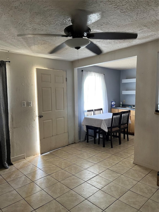 dining area with a textured wall, a ceiling fan, a textured ceiling, and light tile patterned floors