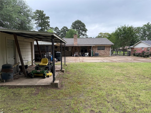 back of property with a carport, a chimney, a yard, and cooling unit