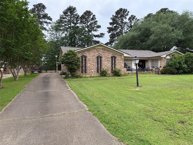 ranch-style home featuring aphalt driveway, brick siding, and a front yard