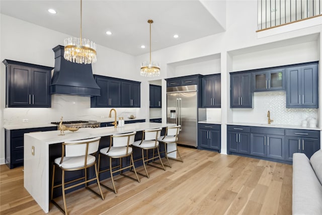 4120 Ridgecrest Dr, Flower Mound, TX 75022 - kitchen featuring stainless steel appliances, a kitchen breakfast bar, a notable chandelier, custom range hood, and light countertops