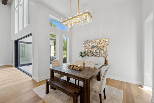 4120 Ridgecrest Dr, Flower Mound, TX 75022 - dining space with light wood-type flooring, a towering ceiling, baseboards, and a notable chandelier