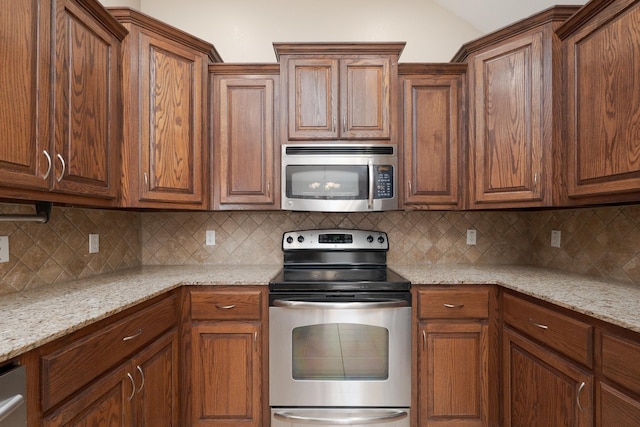 kitchen with decorative backsplash, appliances with stainless steel finishes, and light stone countertops