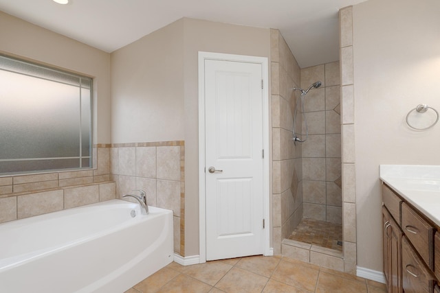 bathroom featuring a tile shower, tile patterned floors, vanity, baseboards, and a garden tub