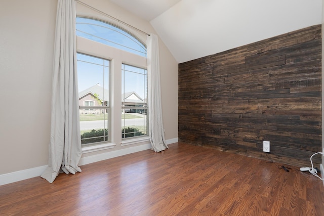 unfurnished room featuring lofted ceiling, baseboards, and dark wood finished floors