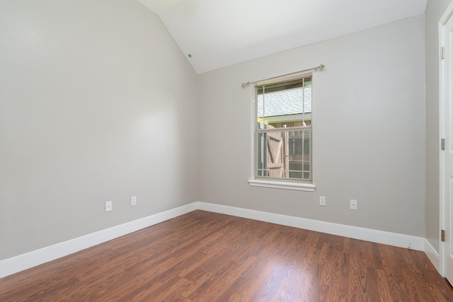spare room with lofted ceiling, dark wood-style flooring, and baseboards