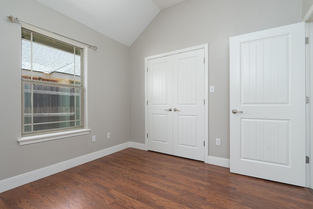 unfurnished bedroom with lofted ceiling, baseboards, a closet, and dark wood finished floors