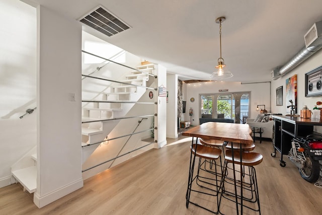 dining room featuring light wood-style flooring, visible vents, and stairs